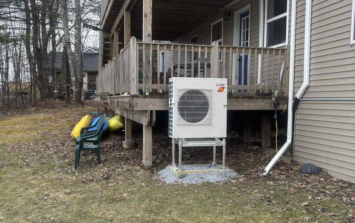 Mitsubishi Hyper-Heat outdoor unit on a stand beside an Upstate NY home