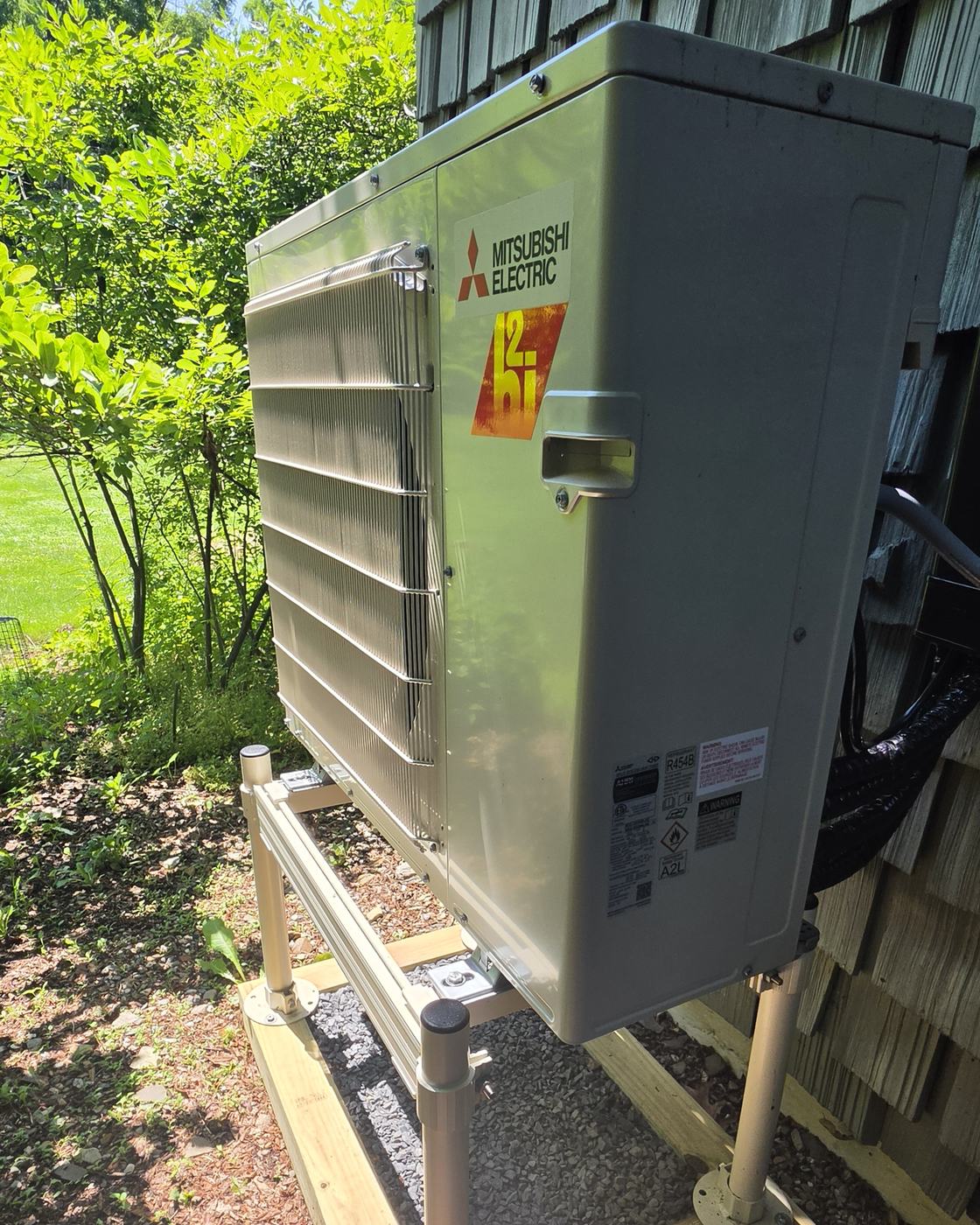 Mitsubishi Hyper-Heat outdoor unit on an aluminum stand over a gravel pad — a Superior CO-OP HVAC installation