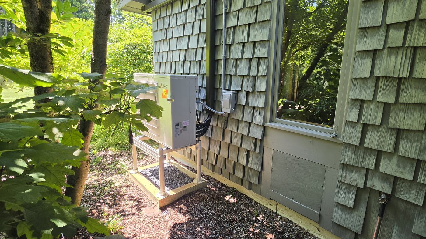 Mitsubishi Hyper-Heat outdoor unit on an aluminum stand beside a shingled Upstate NY home — Superior CO-OP HVAC install