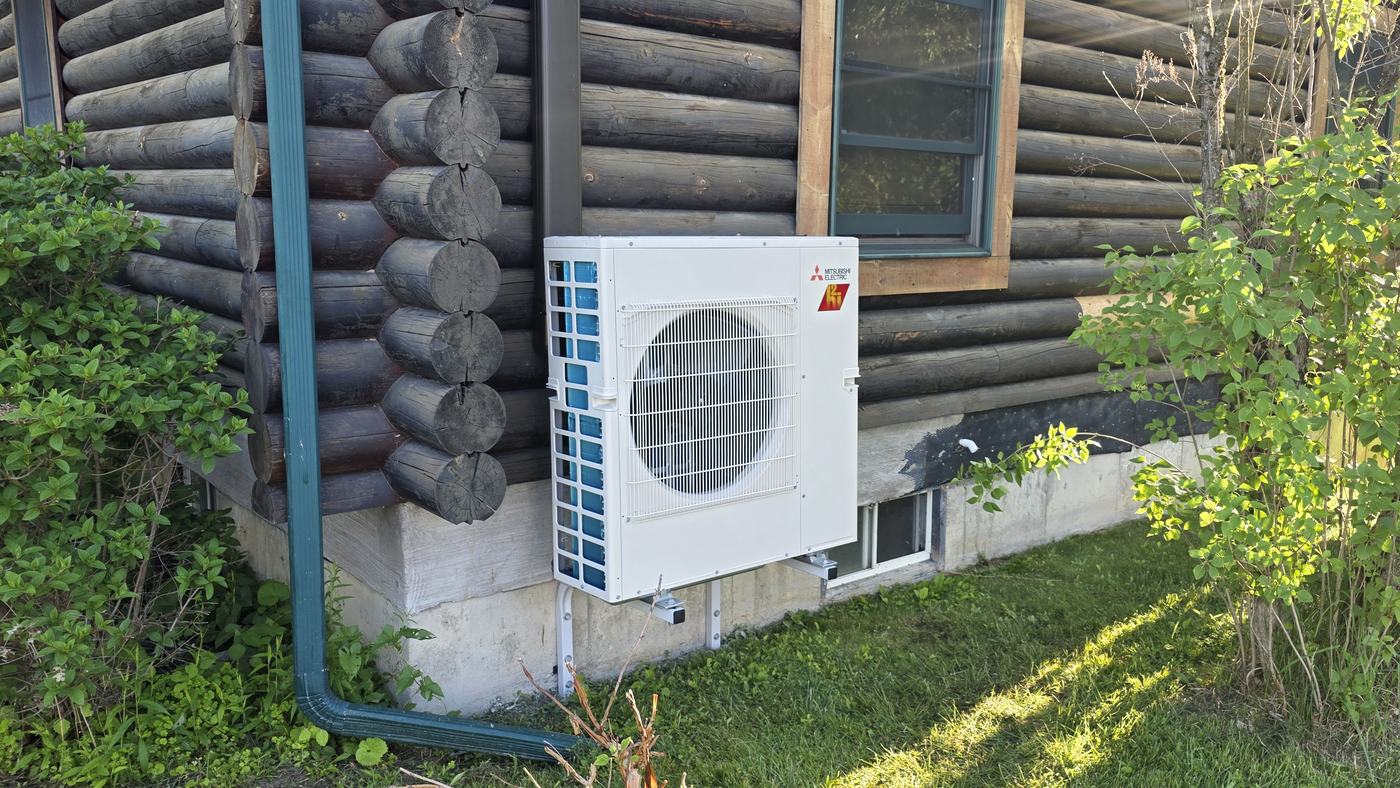 Mitsubishi Hyper-Heat outdoor unit wall-mounted on a log home, installed by Superior CO-OP HVAC